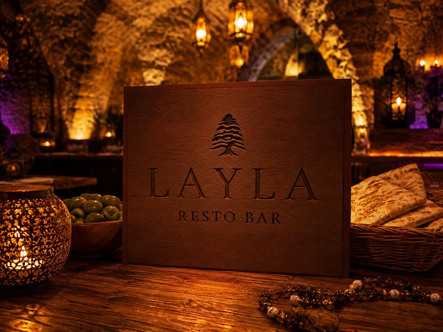 Wooden Layla Resto Bar sign in a stone cellar, surrounded by candles and lanterns